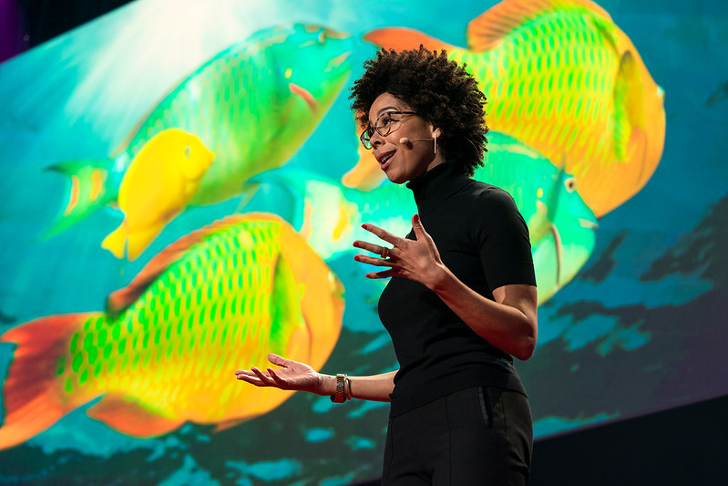 Dr. Ayana Elizabeth Johnson gives a talk with image of fish behind her