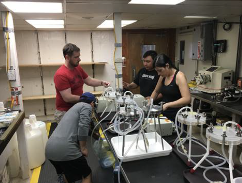 four people adjust filters in a science lab