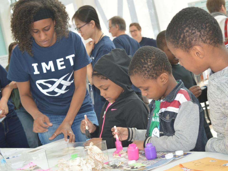 Amanda Lawrence works with children as they paint crabs at the IMET Open House. 
