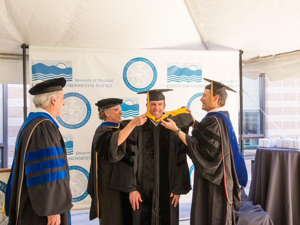 Larry Sanford (right) and Raleigh Hood drape the hood on graduate student Andrew Leight