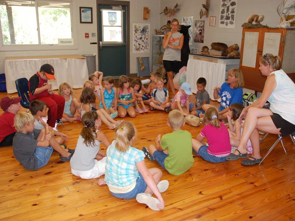 Group of students sitting in a circle listening to a lesson in the Outdoor Education Center