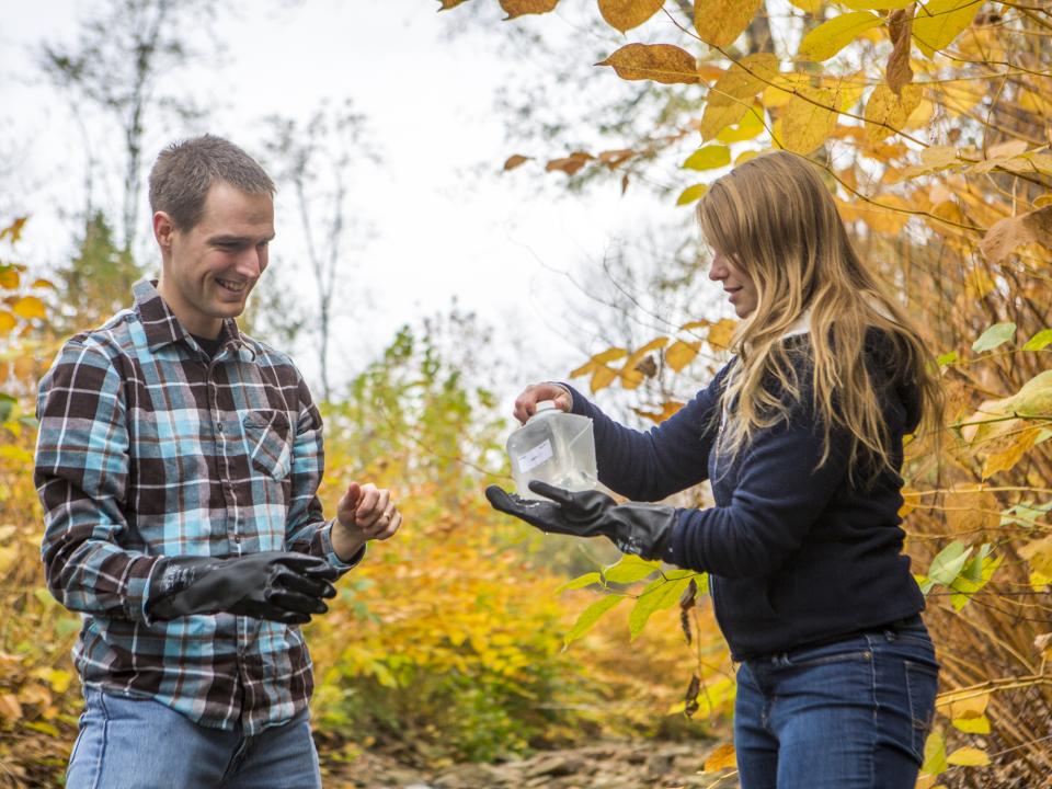 Two students gather a water sample in western Maryland stream