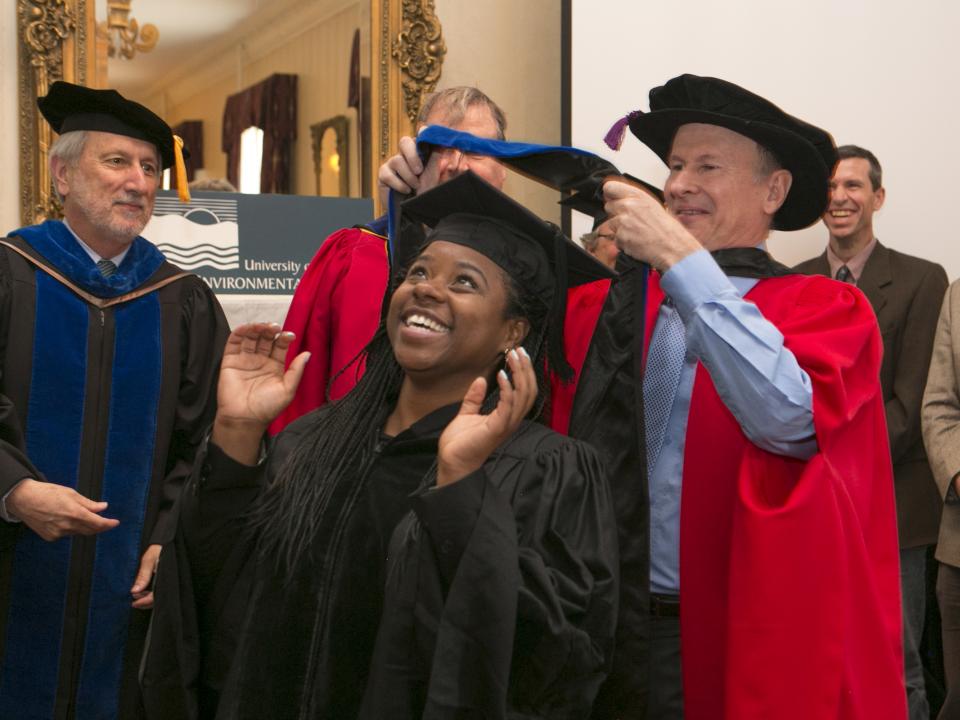 Russell Hill presents a hood to his student Jeannette Davis at commencement in 2015.