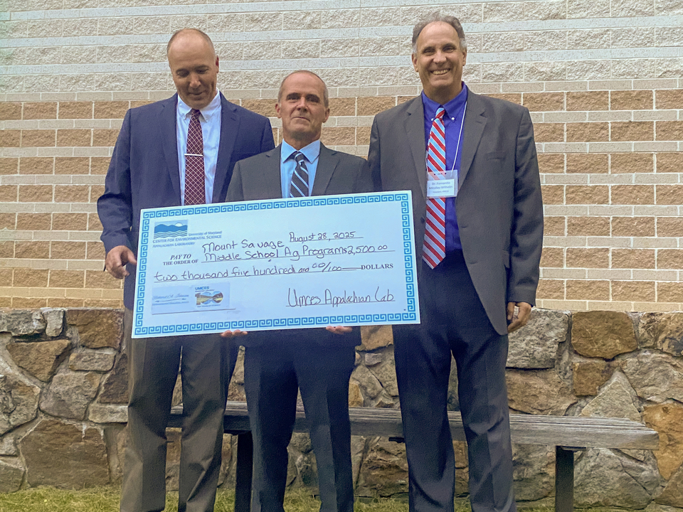 Dr. David Nelson, UMCES Appalachian Laboratory Director; Matthew Kline, 2025 Richard Johnson Environmental Education Award winner; and Dr. Fernando Miralles-Wilhelm, UMCES President standing in front of stone wall with red brick wall in background 