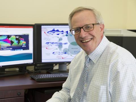 Kenny Rose in front of computer ecosystem model of fishery.