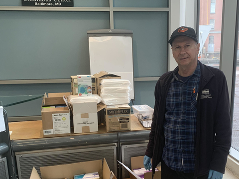 IMET Director Russell Hill stands next to boxes of personal protective gear for the COVID-19 response.