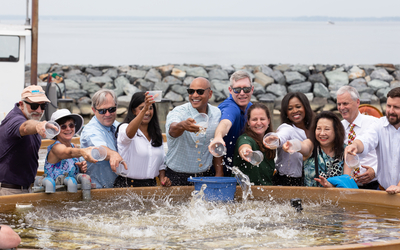 Governor Moore and his cabinet toss oyster spat into a giant vat filled with water
