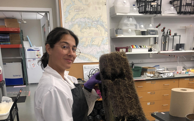 Isabel Sanchez holding a piece of holding wetlands in the lab