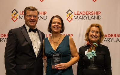 Dr. Carys Mitchelmore in the center. A man and woman representing Leadership Maryland are at her sides.