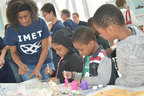 Amanda Lawrence works with children as they paint crabs at the IMET Open House. 