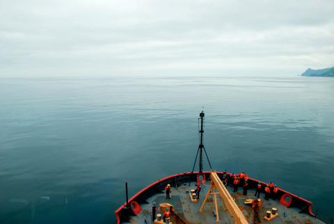 USCGC Healy peeks into frame as it cruises through Arctic waters.