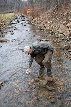 Taking a water sample in a stream.