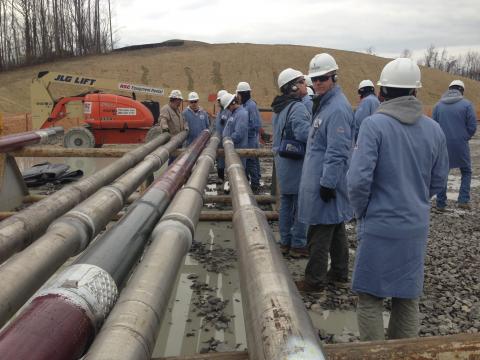 workers gather around pipes to allow oil drilling.