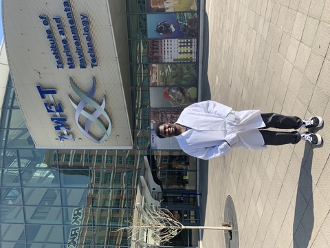 Abdul Adaranijo in a lab coat outside of IMET