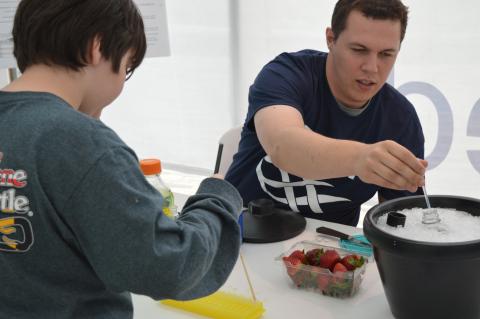 IMET graduate student Ryan McDonald shows a visitor to the Open House how to extract DNA from a strawberry.