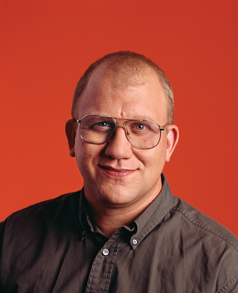 Headshot of Dr. Bill Fagan in brown button down shirt with red background. 