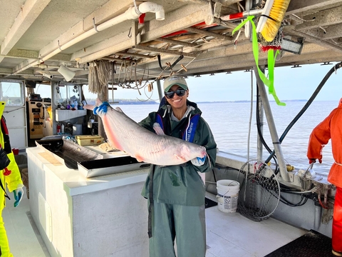 Samara holding an invasive blue catfish on a boat