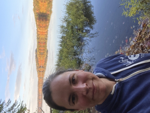 Dr. Kelly Pearce with water and fall foliage in background. 