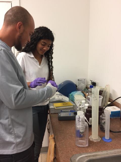 Two students examine samples in a lab.