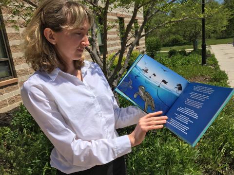 Helen Bailey holds up her children's book, the Grande Turtle Adventure.