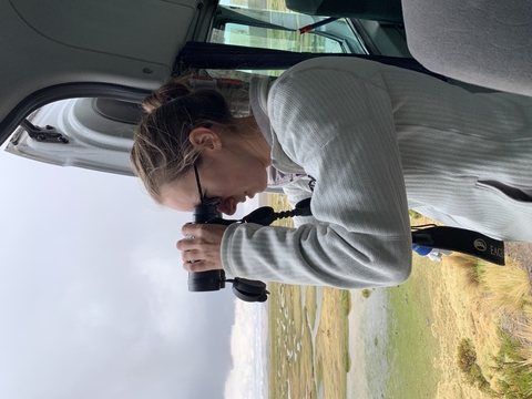 Close up of Dr. Joely DeSimone in grey observing through binoculars. 