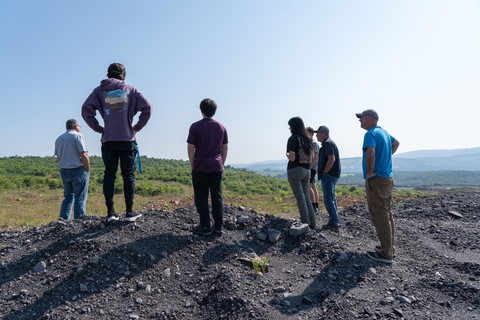 interns and standing on pile of coal looking out across a meadow of grasses. 