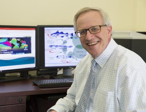 Kenny Rose in front of computer ecosystem model of fishery.