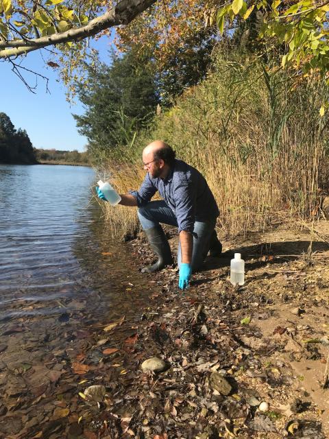 Louis Plough a collects a water sample to test for DNA evidence of river herring in the lab.