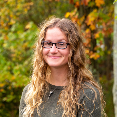 Claire Nemes wearing a grey sweater with orange and green foliage in background