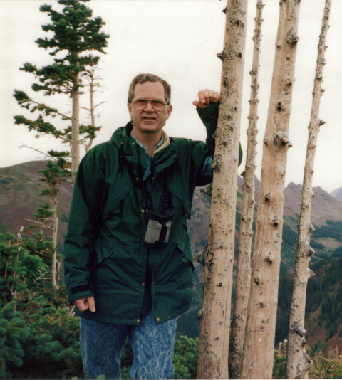 Dr. Richard Johnson outdoors, leaning against a tree and facing camera. 