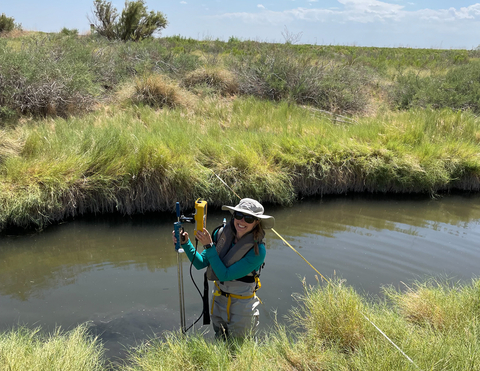 Stephanie Siemek standing in creek holding research equipment. 