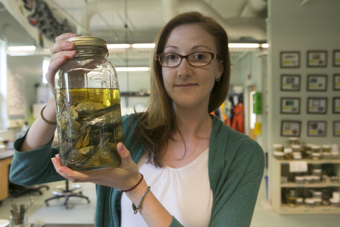 Alumni holding a jar of specimen in a lab