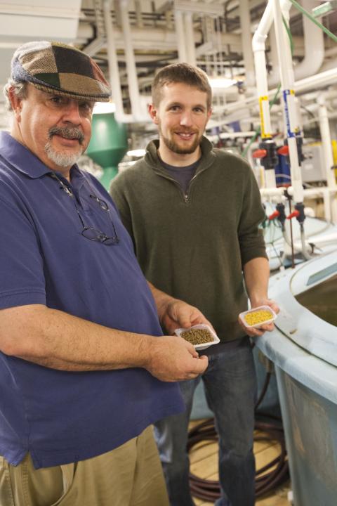 Aaron Watson alumni with advisor Al Place holding vegetarian fish meal