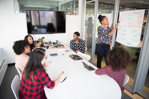 Adults brainstorming around conference room table. 