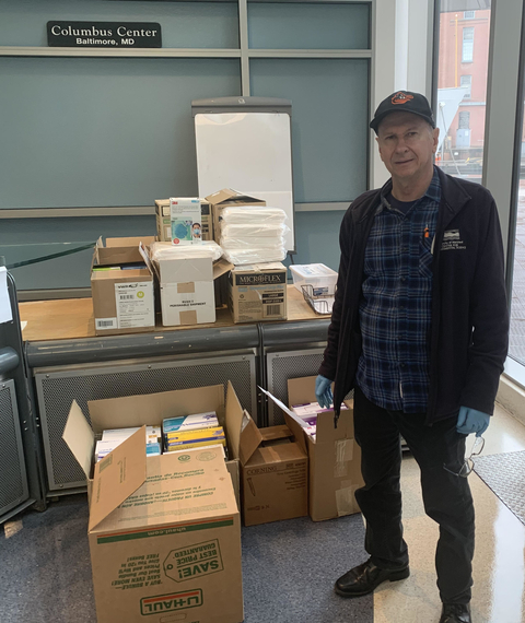 IMET Director Russell Hill stands next to boxes of personal protective gear for the COVID-19 response.