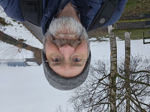 Headshot of Dr. Jeff Buler in blue coat and grey knitted cap with a snowy landscape as background 