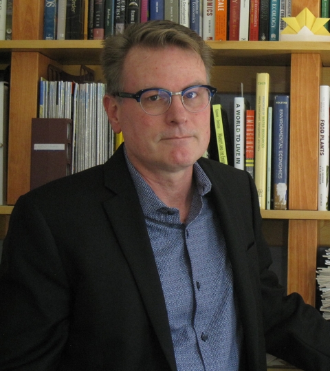 Dr. Bill Currie in front of book shelf. 