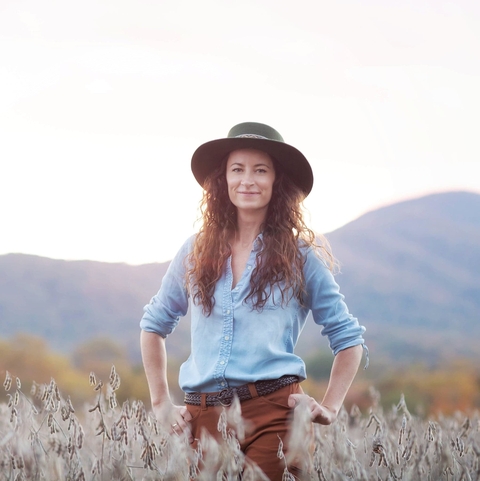 Amy Johnson standing in a field with mountains in the background. 