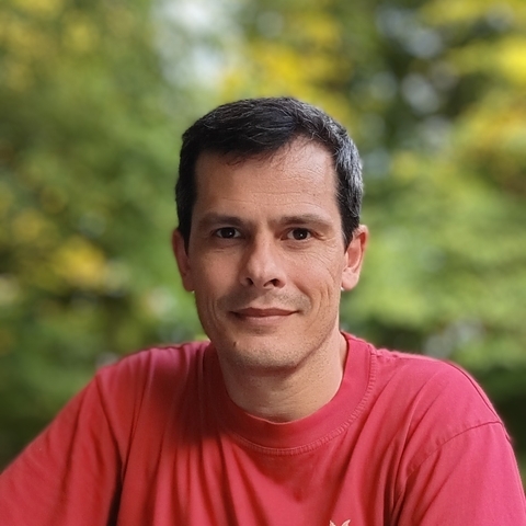 Headshot of Joaquin Martinez Martinez in red shirt with blurred trees in background. 