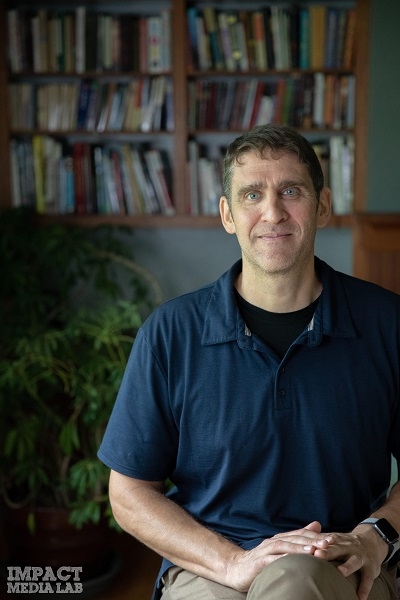 Dr. Phil Townsend sitting in front of a book shelf with "impact global lab" in lower left corner. 