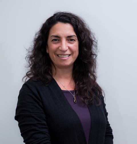 Head shot of Tina Phillips smiling toward camera wearing black cardigan with a light grey background. 