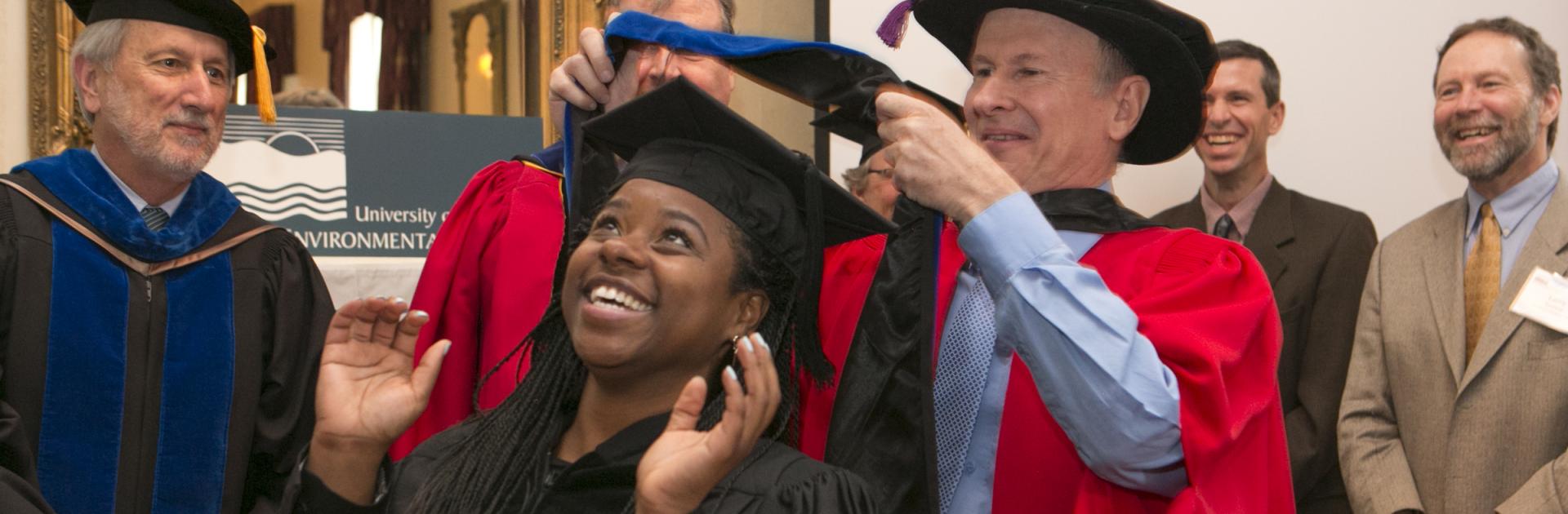 Russell Hill presents a hood to his student Jeannette Davis at commencement in 2015.