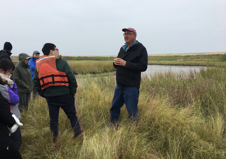 Jeff Cornwell Speaking to students on Poplar Island among marsh grass