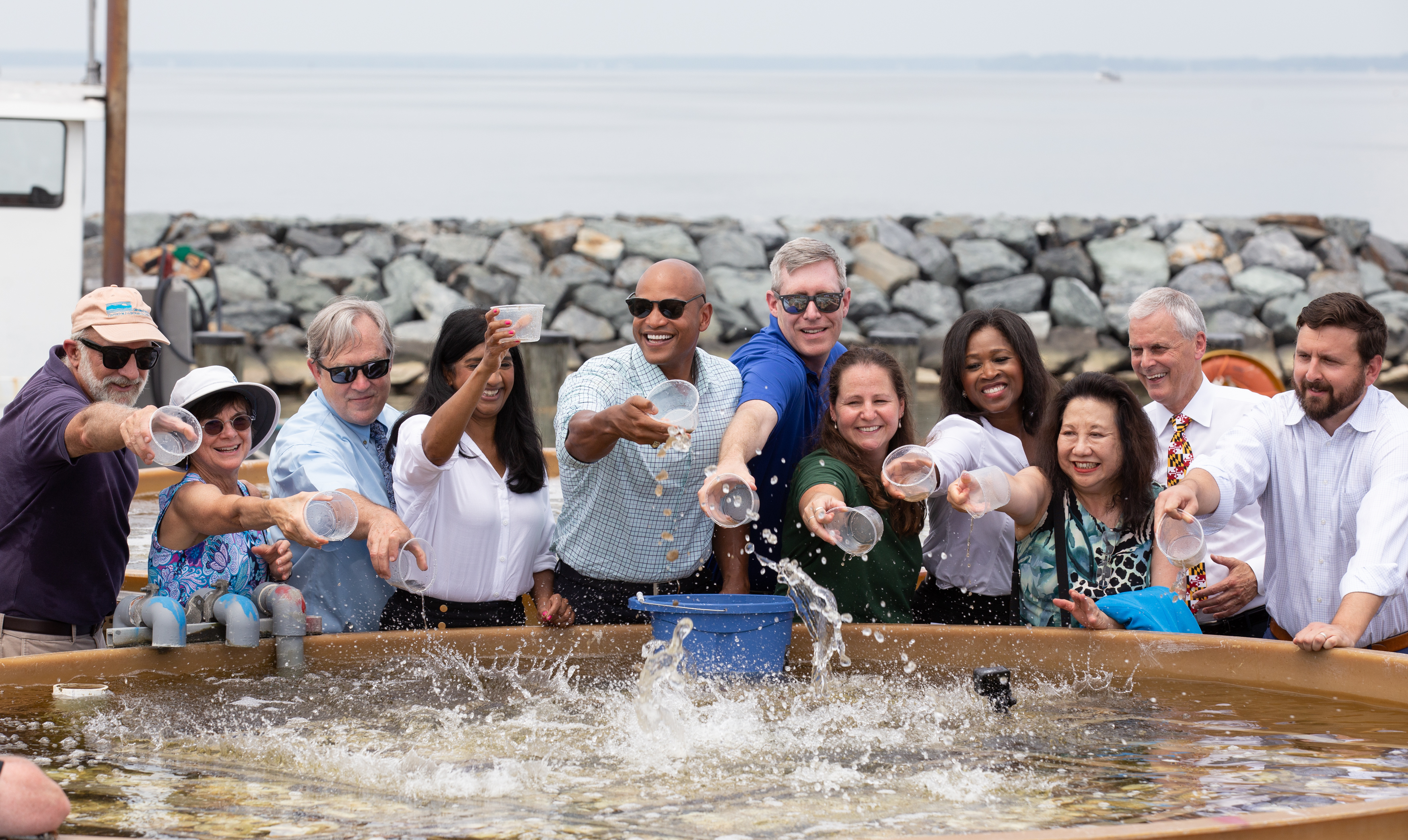 A group of politicians and UMCES' community splash oyster spat into a setting tank
