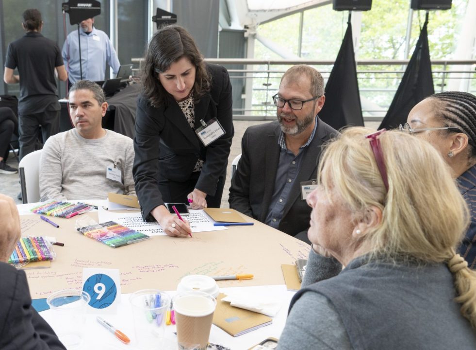 Alexa Fries shares information with a table of seated observers