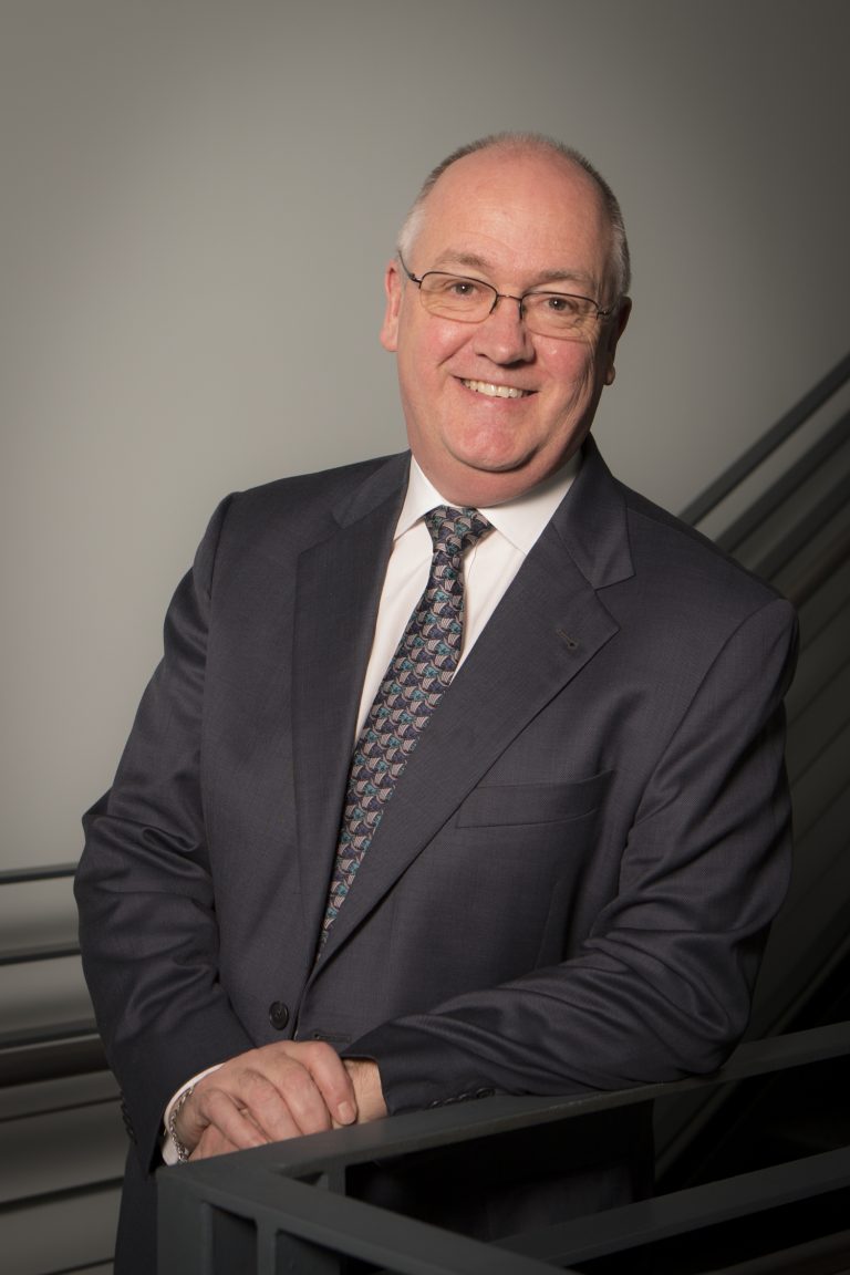 Dr. Tom Miller dressed in a dark suit and tie
