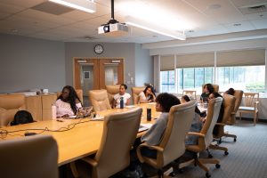The IMET summer interns are paying attention to Dr. Lamba at a conference table