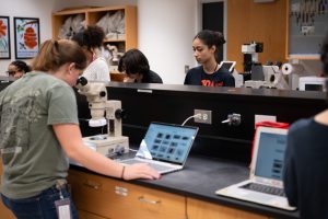 An intern looking into a microscope and using a computer