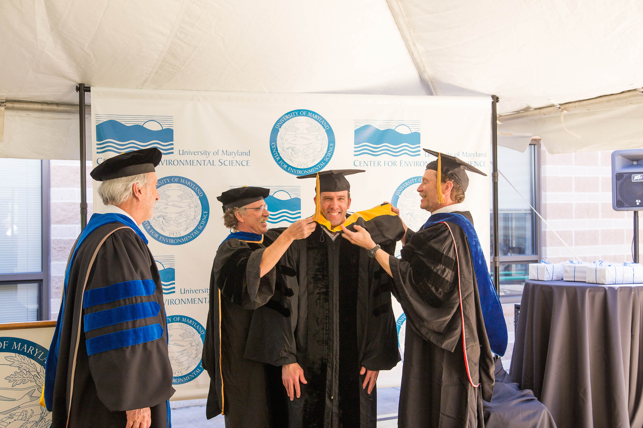 Larry Sanford (right) and Raleigh Hood drape the hood on graduate student Andrew Leight