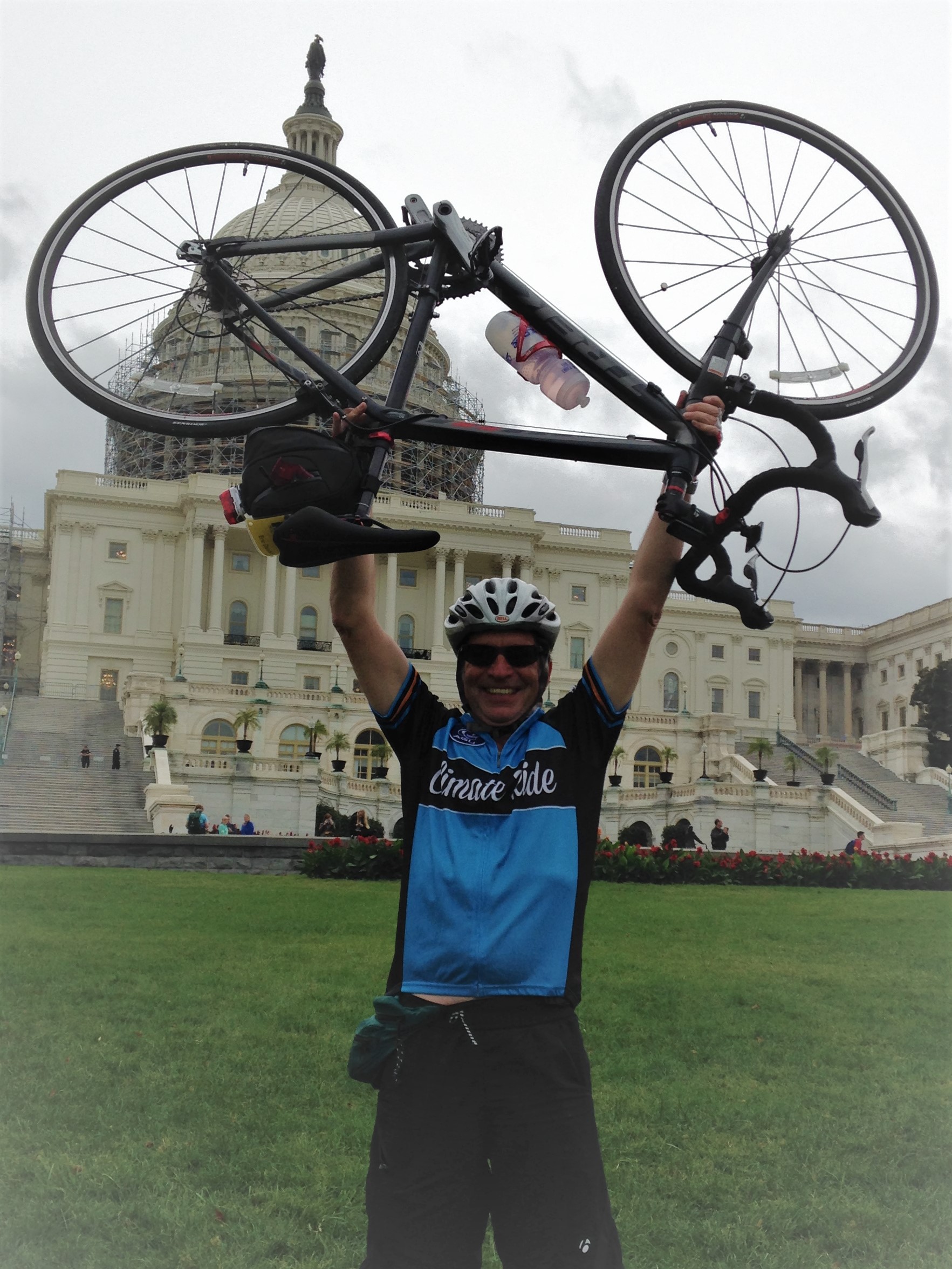 Eric Davidson hoists up his bike in front of Washington DC's Capitol after completing a Climate Ride.